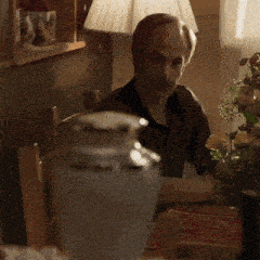 a man sitting at a table with a lamp and flowers