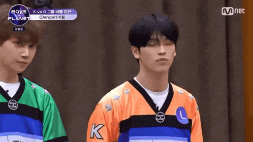 two boys are standing next to each other wearing jerseys with the letter k on them .