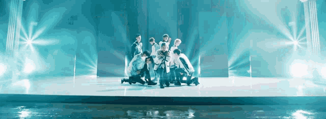 a group of people are dancing on a stage in front of a blue background
