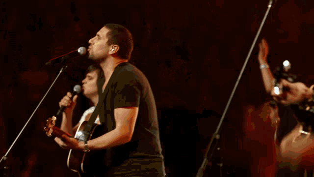 a man in a white shirt is playing a guitar in front of a crowd