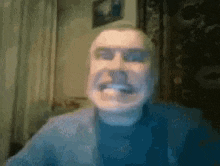a man is making a funny face while looking at the camera in a blurry photo .