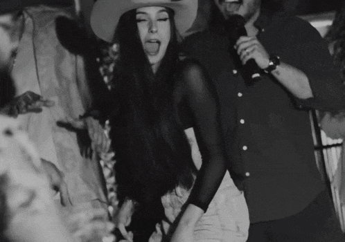 a woman wearing a cowboy hat is dancing in a crowd