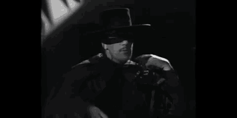 a black and white photo of a man wearing a mask and a hat with the words parle je t'écoute in the corner