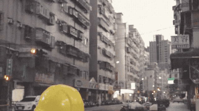 a yellow helmet is in the middle of a busy street in front of a building with a sign that says family mart