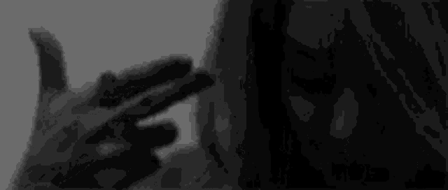 it is a black and white photo of a person making a peace sign .