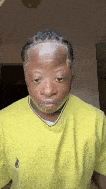 a young man with a shaved head is wearing a yellow polo shirt .