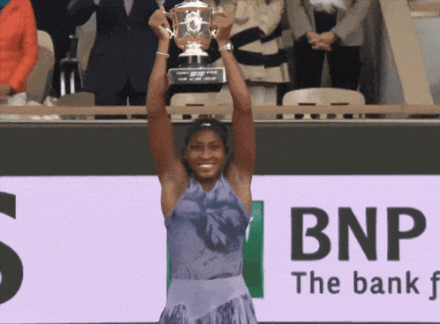 a woman is holding a trophy in front of an ad for bnp