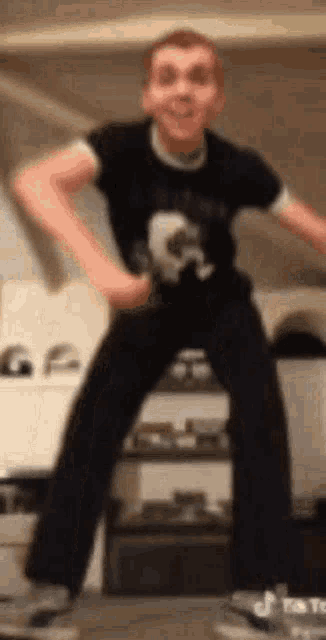 a boy in a black shirt and black pants is dancing in a room .