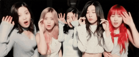 a group of girls are standing next to each other with their hands up in the air .