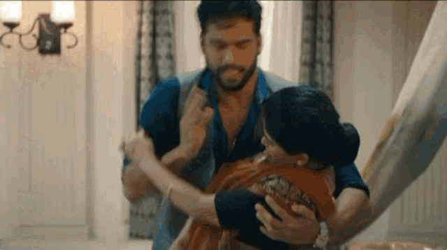 a man is holding a woman in his arms while they are dancing in a room .