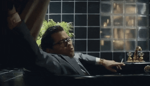 a man in a suit and tie is laying in a bathtub