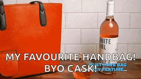 a bottle of white girl wine sits next to an orange handbag