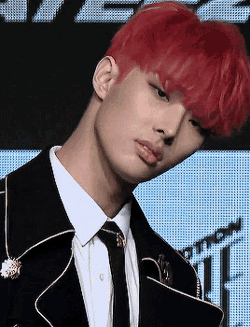 a man with red hair is wearing a black suit and tie