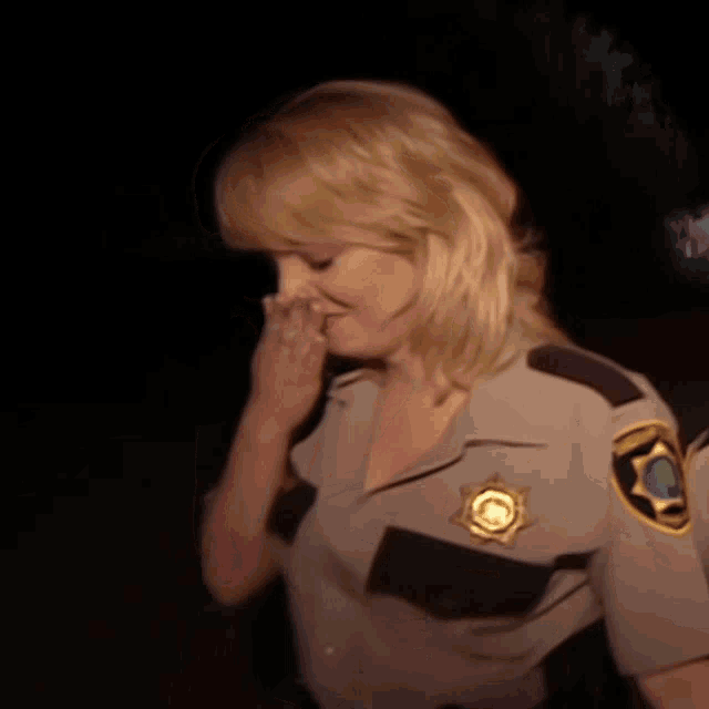 a woman in a sheriff 's uniform is covering her nose with her hand and the words alright are below her