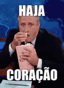 a man in a suit and tie is eating popcorn and has the word haja on his face