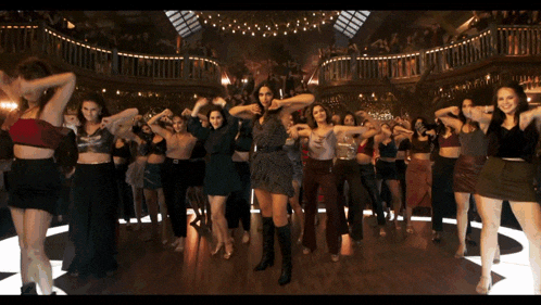 a group of women are dancing together in a large room
