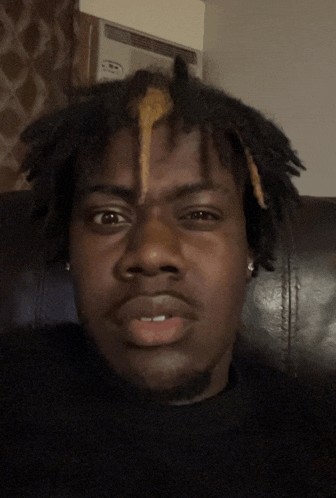 a man with dreadlocks has a yellow stripe in his hair