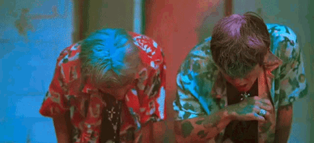 two young men are standing next to each other with their faces covered in green paint .