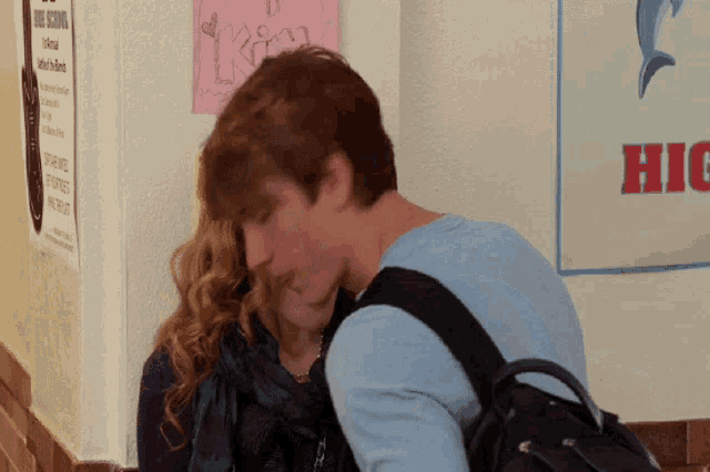 a boy and a girl are kissing in front of a sign that says hig