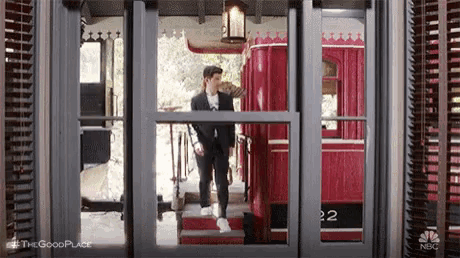 a man in a suit is walking through a doorway to a red bus .