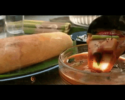 a sandwich is being poured into a bowl of sauce
