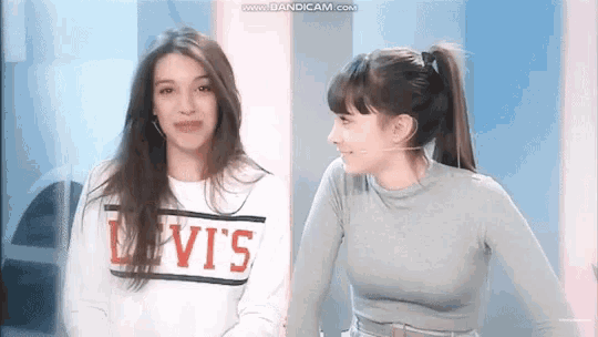 two women are standing next to each other and one of them is wearing a sweater that says levis .