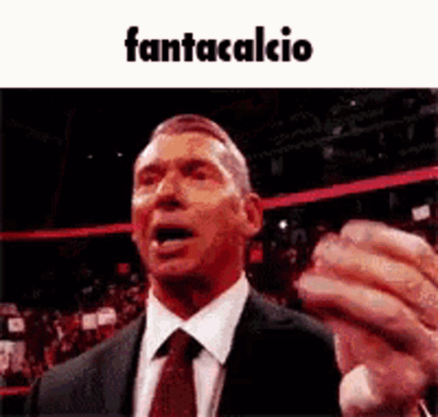 a man in a suit and tie is making a funny face and the word fantacalcio is on the bottom .