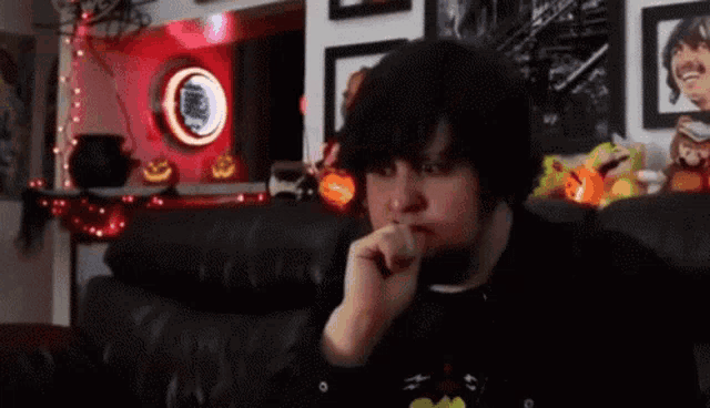a man is sitting on a couch smoking a cigarette in front of a halloween decoration .