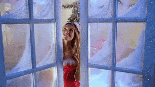 a woman dressed as santa claus is looking out of a window .