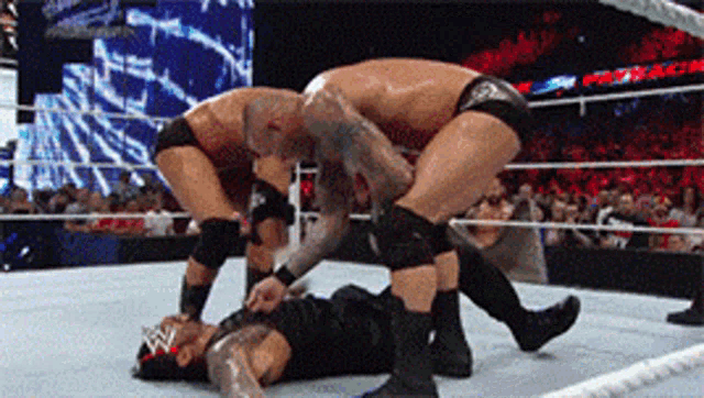 two men are wrestling in a wrestling ring and one of them is wearing a w logo on his head