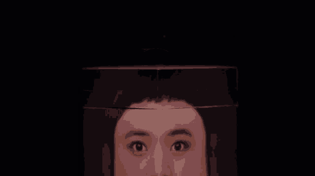 a close up of a woman 's face with a candle behind it