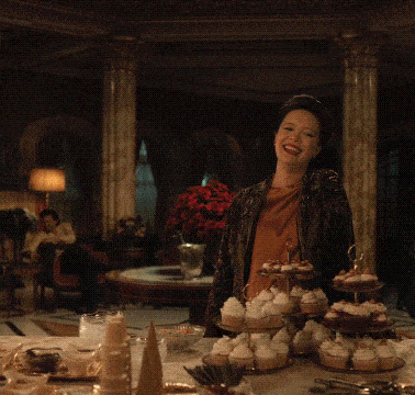 a woman is standing in front of a table with cupcakes on it