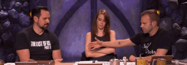 three people sitting at a table with one wearing a shirt that says the last of us