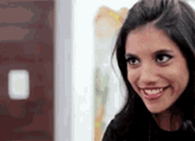 a woman is smiling and looking at the camera in a room .