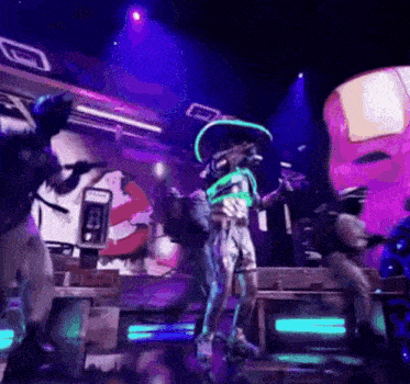 a group of people are dancing on a stage with a ghostbusters sign in the background