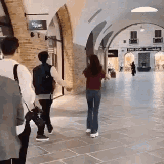 a man and a woman are holding hands while walking through a mall .