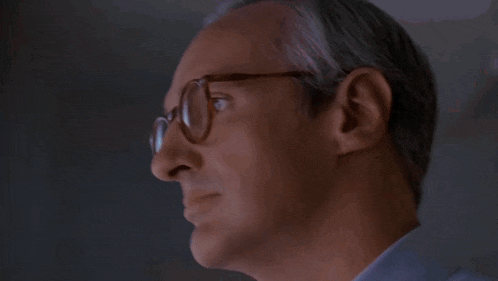 a close up of a man wearing glasses looking out of a window