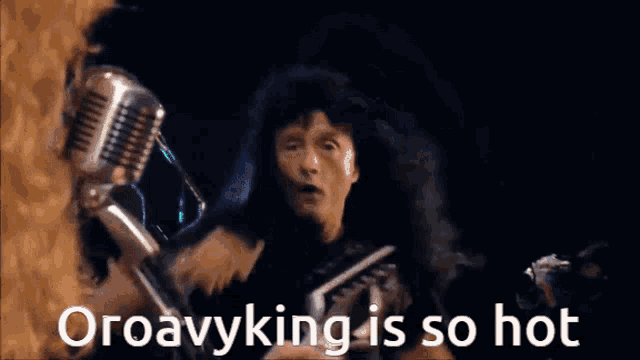 a man is singing into a microphone with the words oroavyking is so hot written below him
