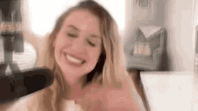 a woman is smiling with her eyes closed in a room .