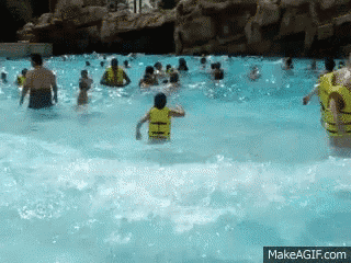 a group of people are swimming in a water park and one of them is wearing a life jacket