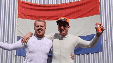 two men standing in front of a flag holding a can