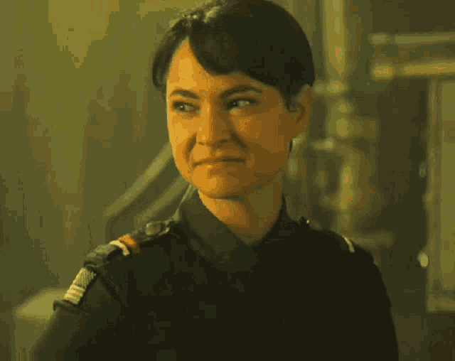 a woman in a military uniform is smiling and looking at the camera