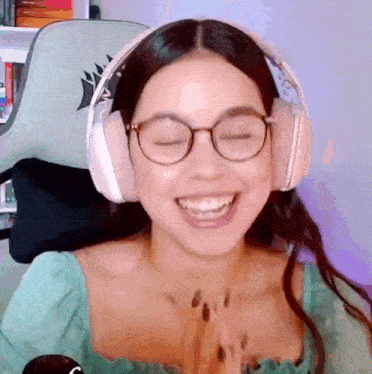 a woman wearing glasses and headphones is smiling while sitting in a chair .