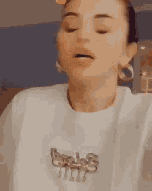 a close up of a woman wearing a white t-shirt and earrings