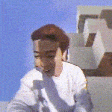 a man with red hair and a white shirt is standing in front of a blue sky