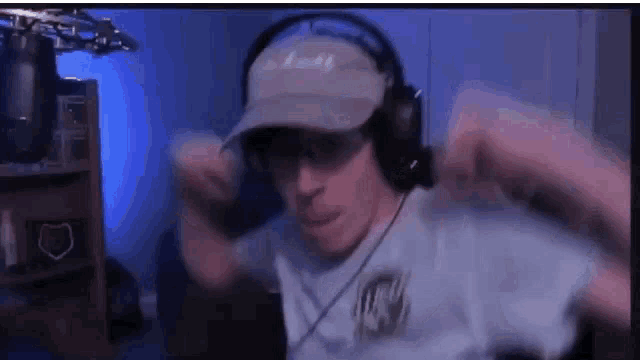 a man wearing headphones and a hat is sitting in front of a microphone in a room .