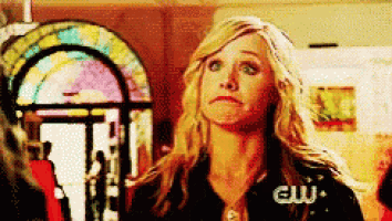 a woman is making a funny face in front of a stained glass window with the word cw on her shirt .