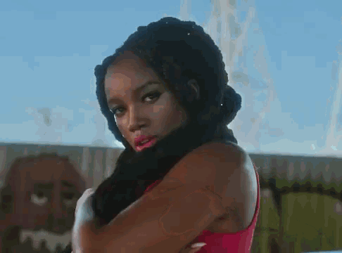 a woman in a red tank top is standing in front of a fence .