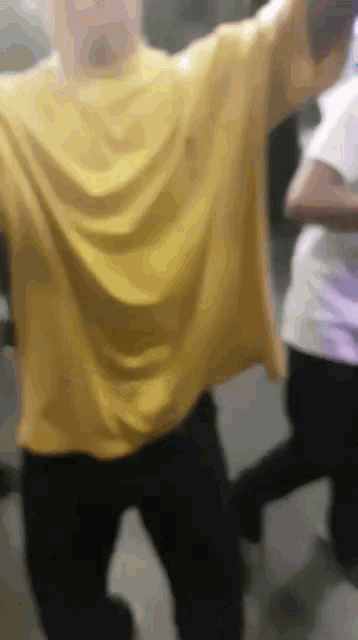 a man in a yellow shirt is dancing with his arms in the air