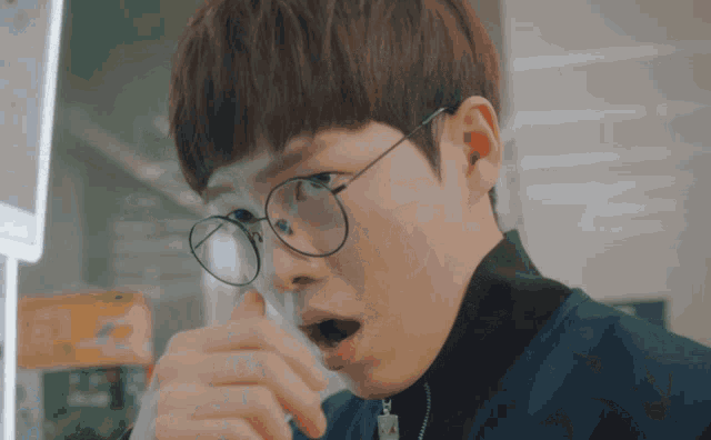 a man wearing glasses and a blue jacket looks surprised